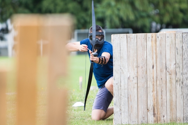  Bogenschießen-Tag-Spieler hinter seinem Versteck 