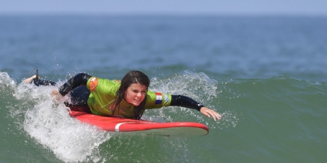  Surfschüler schwimmt auf der Welle. 